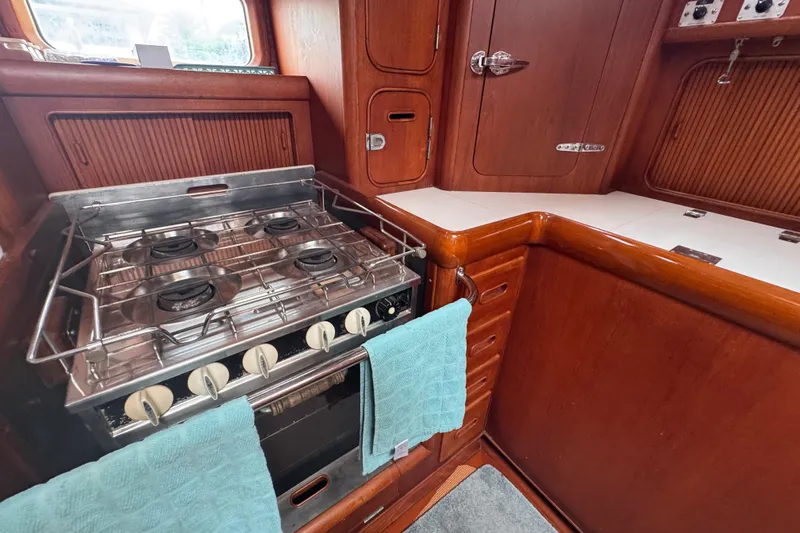 Entertainer Yacht Photos Pics Galley kitchen in 1989 Little Harbor Sloop, featuring a four-burner stove and wooden cabinetry.