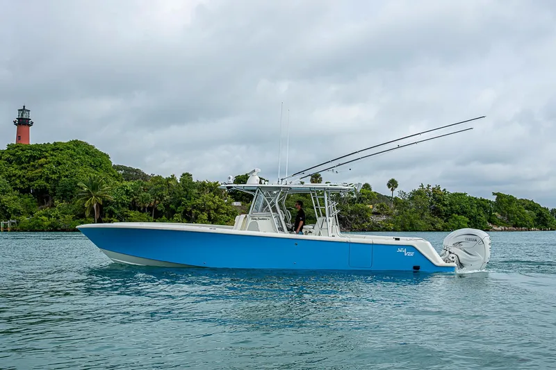 Fishy Business Yacht Photos Pics 2014 SeaVee 390B boat cruising near a lighthouse, surrounded by lush greenery.