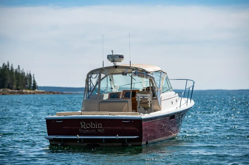 Robin Yacht Photos Pics 2005 Hunt Yachts Surfhunter 29 on calm water, rear view, with coastal background.