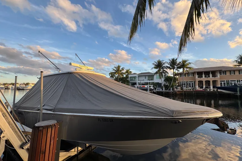  Yacht Photos Pics 2021 Everglades 335 Center Console boat covered at a marina, surrounded by palm trees.