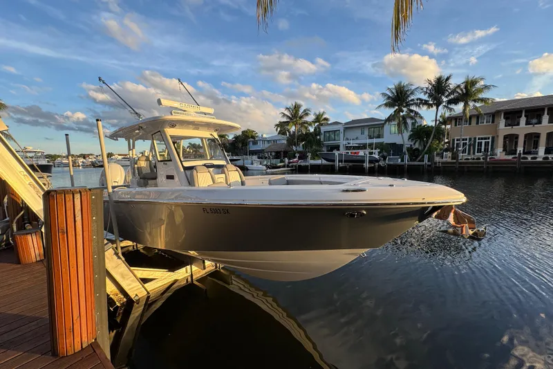  Yacht Photos Pics 2021 Everglades 335 Center Console boat docked by waterfront homes under a blue sky.