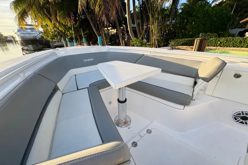  Yacht Photos Pics 2021 Everglades 335 Center Console boat interior with seating and table, docked near palm trees.
