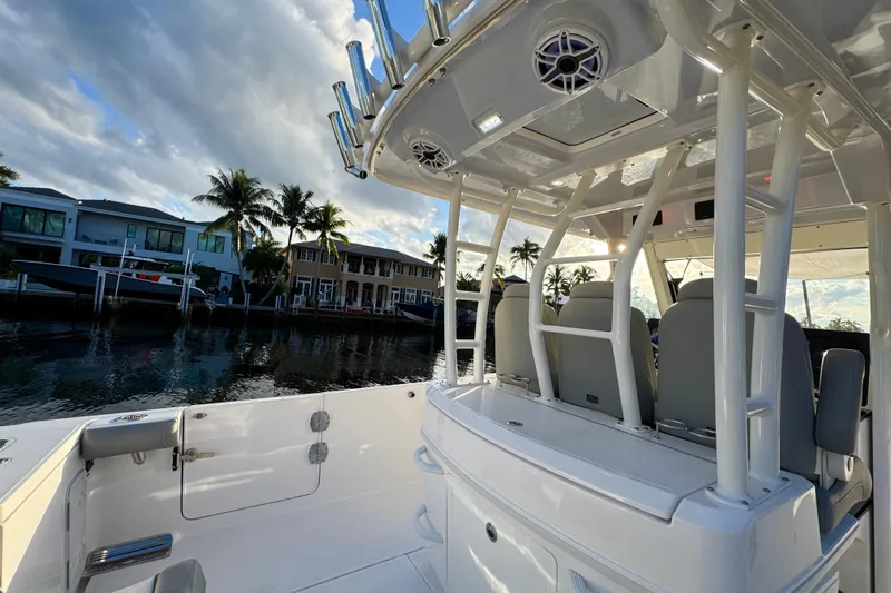 Yacht Photos Pics 2021 Everglades 335 Center Console boat docked by waterfront homes, under a cloudy sky.