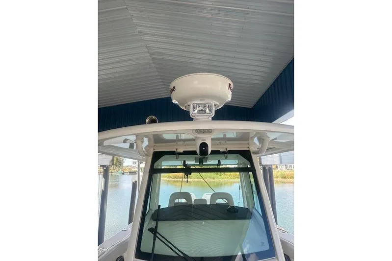  Yacht Photos Pics 2016 Boston Whaler 330 Outrage boat with radar, docked under a metal roof.