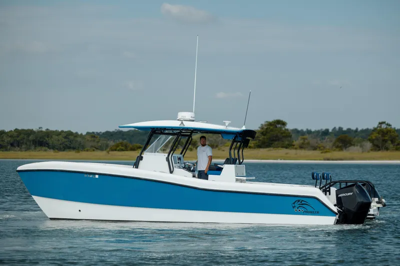  Yacht Photos Pics 2020 Prowler 31 boat on water, blue and white design, with a person onboard.