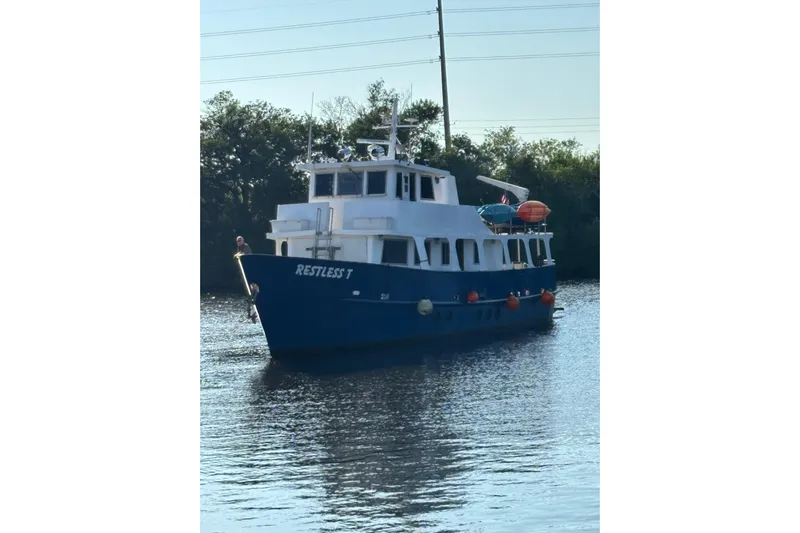 Restless T Yacht Photos Pics Blue 1971 Sermons Expedition boat "Restless T" on calm water, surrounded by trees.