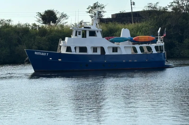 Restless T Yacht Photos Pics 1971 Sermons Expedition boat "Restless T" on calm water with kayaks on deck.