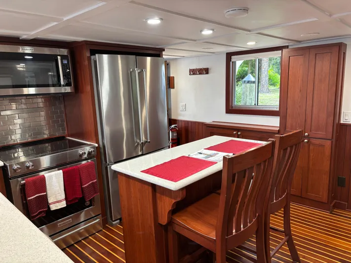 Restless T Yacht Photos Pics Modern kitchen interior in a 1971 Sermons Expedition boat, featuring wood accents and stainless steel appliances.