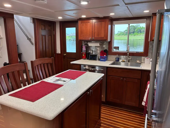 Restless T Yacht Photos Pics 1971 Sermons Expedition yacht kitchen with wooden cabinets, island, and river view.