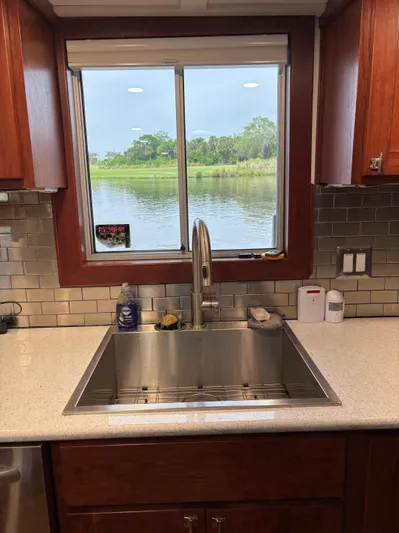 Restless T Yacht Photos Pics Kitchen sink with stainless steel fixtures, overlooking a scenic river view through a window.