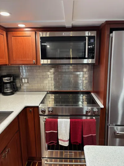 Restless T Yacht Photos Pics Modern kitchen with stainless steel appliances, red accents, and wooden cabinetry in a 1971 Sermons Expedition.