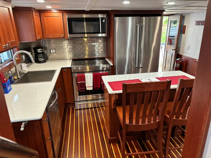 Restless T Yacht Photos Pics Modern kitchen in a 1971 Sermons Expedition boat with wood flooring and stainless steel appliances.