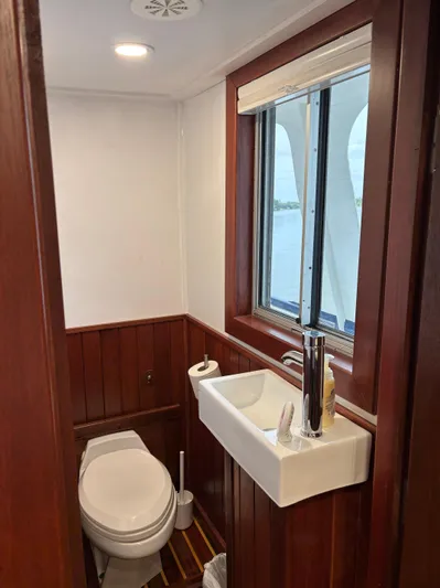 Restless T Yacht Photos Pics 1971 Sermons Expedition boat bathroom with wooden paneling, compact sink, and window view.