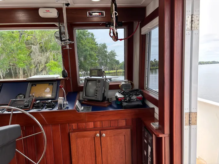 Restless T Yacht Photos Pics 1971 Sermons Expedition boat cockpit with navigation equipment and wooden interior, overlooking a scenic river.