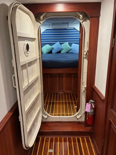 Restless T Yacht Photos Pics Nautical-themed cabin interior with open hatch door, wooden flooring, and colorful cushions.