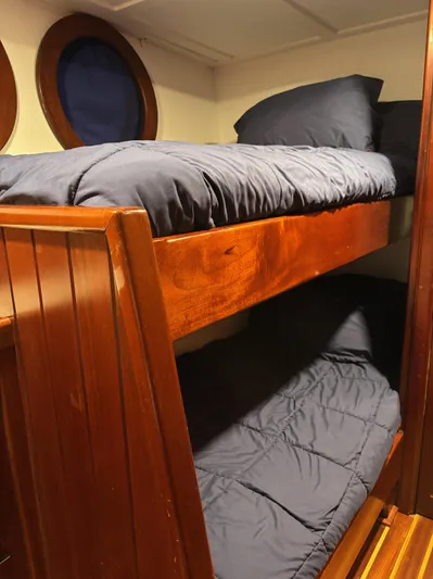 Restless T Yacht Photos Pics Wooden bunk beds with navy bedding in a 1971 Sermons Expedition boat cabin.