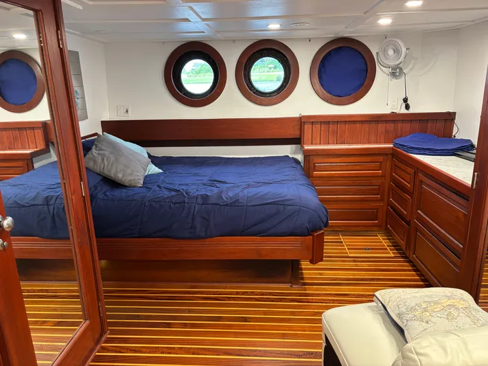 Restless T Yacht Photos Pics Cozy 1971 Sermons Expedition boat cabin with wooden interior, blue bedding, and porthole windows.