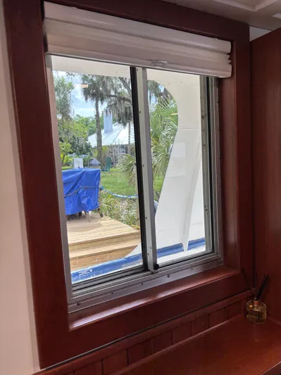 Restless T Yacht Photos Pics Wooden-framed window view from 1971 Sermons Expedition boat, overlooking greenery and deck.