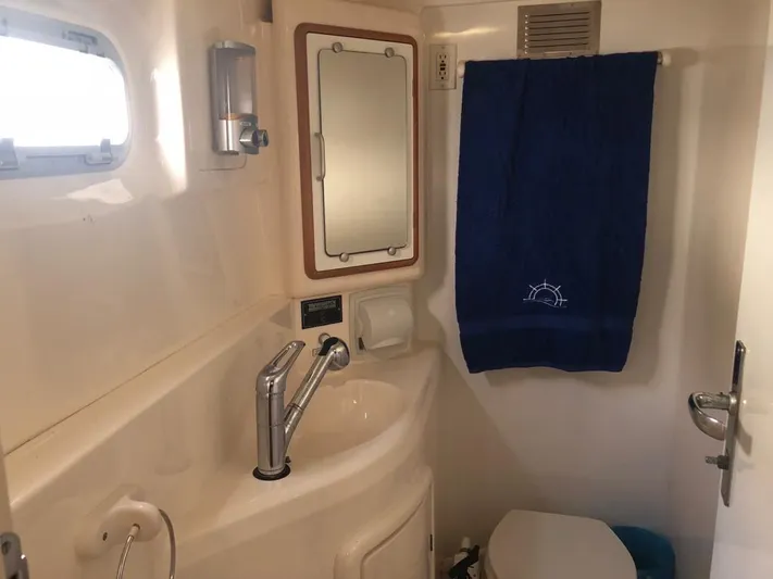 U Turn Yacht Photos Pics Compact bathroom in 2003 Leopard 47 yacht with sink, mirror, and blue towel.