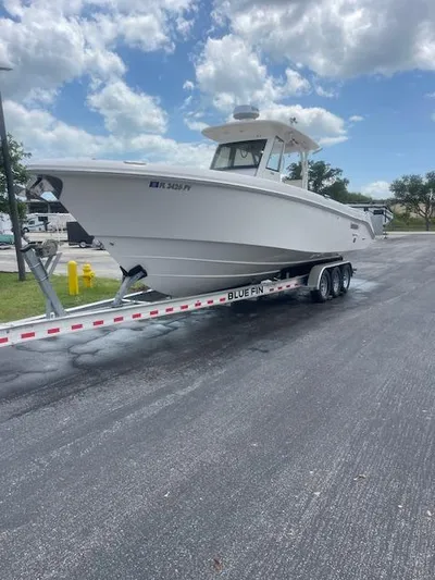  Yacht Photos Pics 2014 Everglades 325 Center Console boat on trailer, parked on asphalt under cloudy sky.