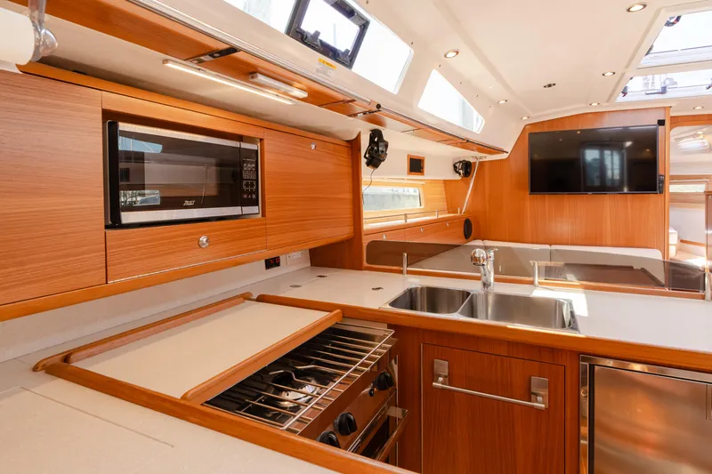 Age Gap Yacht Photos Pics Modern kitchen interior of 2023 Catalina 425 yacht with wood finish and stainless steel appliances.