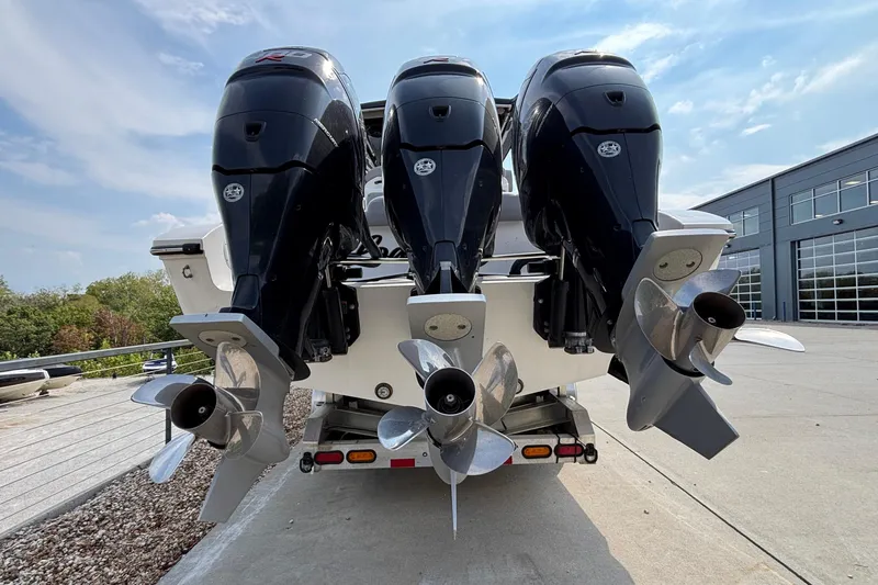  Yacht Photos Pics Triple outboard motors on a 2022 Fountain 38 SC boat, parked outdoors.