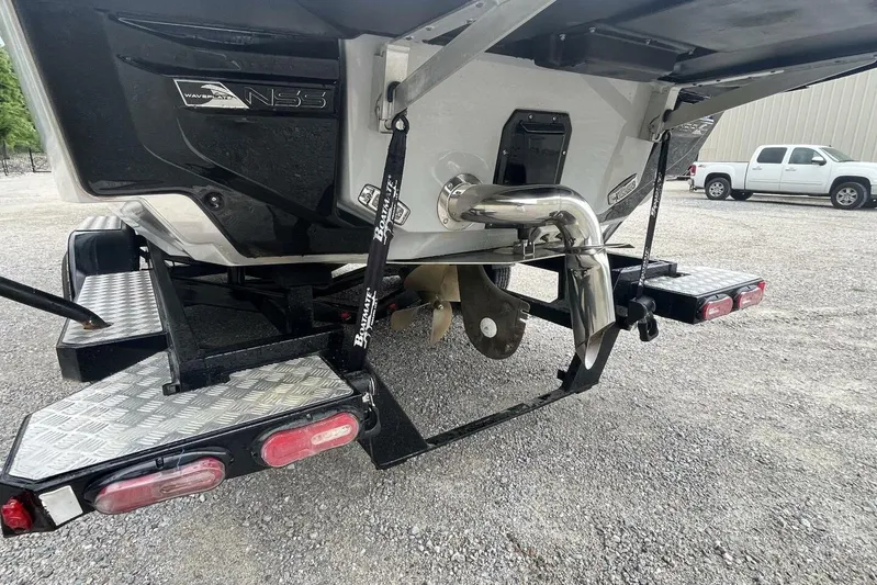  Yacht Photos Pics 2022 Nautique Super Air Nautique G23 boat trailer with NSS system, parked on gravel.