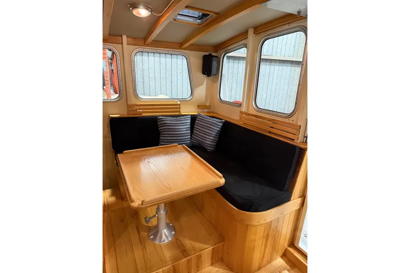 Chad-m Yacht Photos Pics Interior of 2022 Covey Island 38 Lobster Yacht with wooden table and cushioned seating.