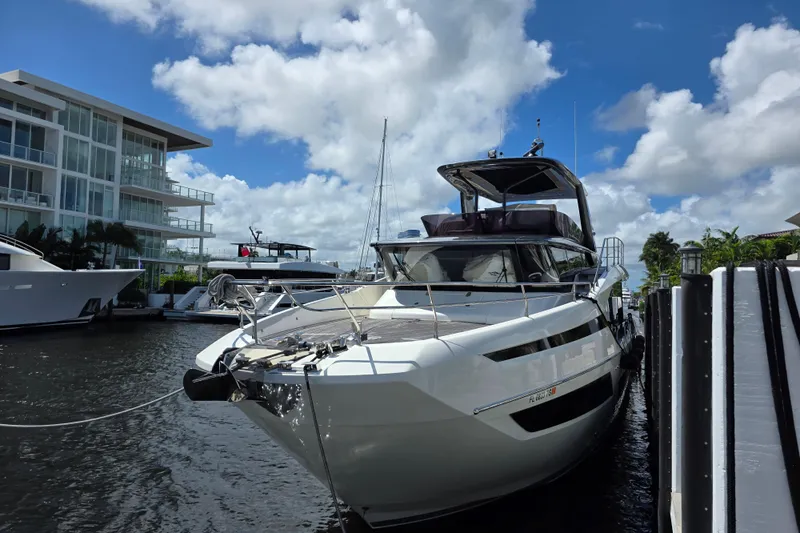  Yacht Photos Pics Luxury 2022 Prestige X70 yacht docked by modern waterfront building under blue sky.