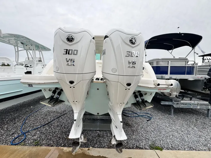  Yacht Photos Pics 2025 Sailfish 316 DC boat with dual Yamaha 300 V6 outboard engines, docked on gravel.