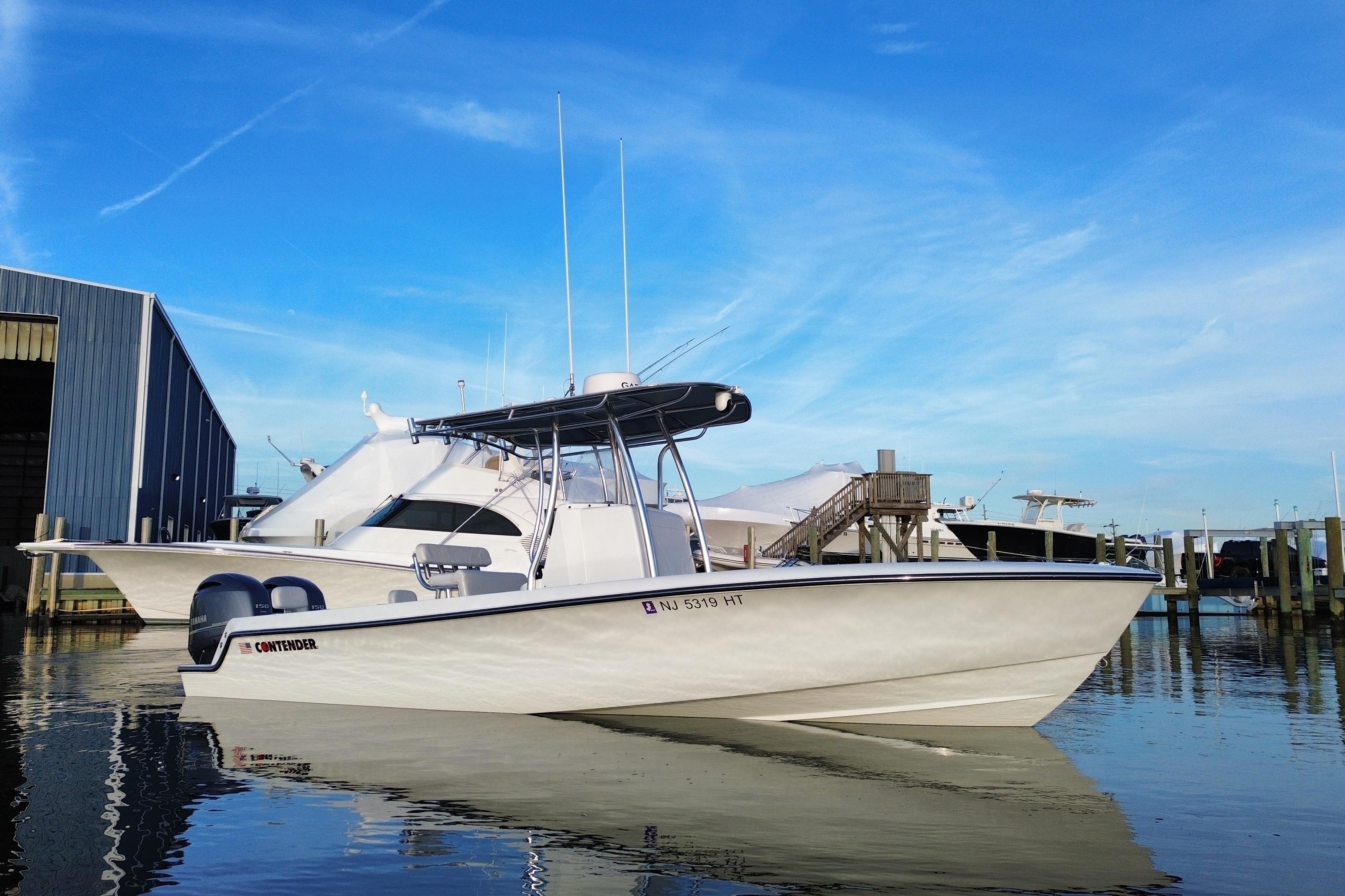 2023 Contender 24 Sport boat docked at marina under clear blue sky.
