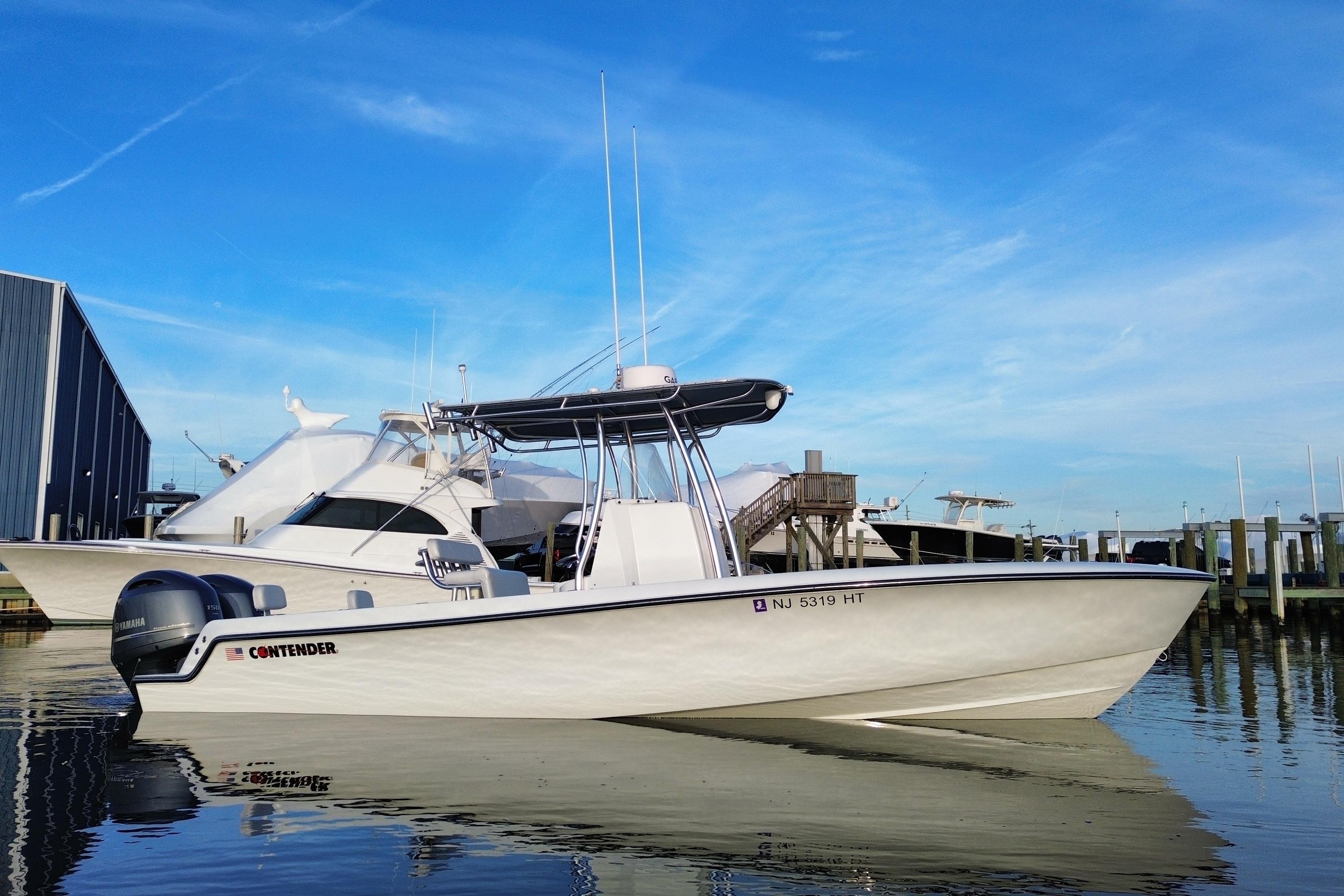 2023 Contender 24 Sport boat docked at marina under clear blue sky.