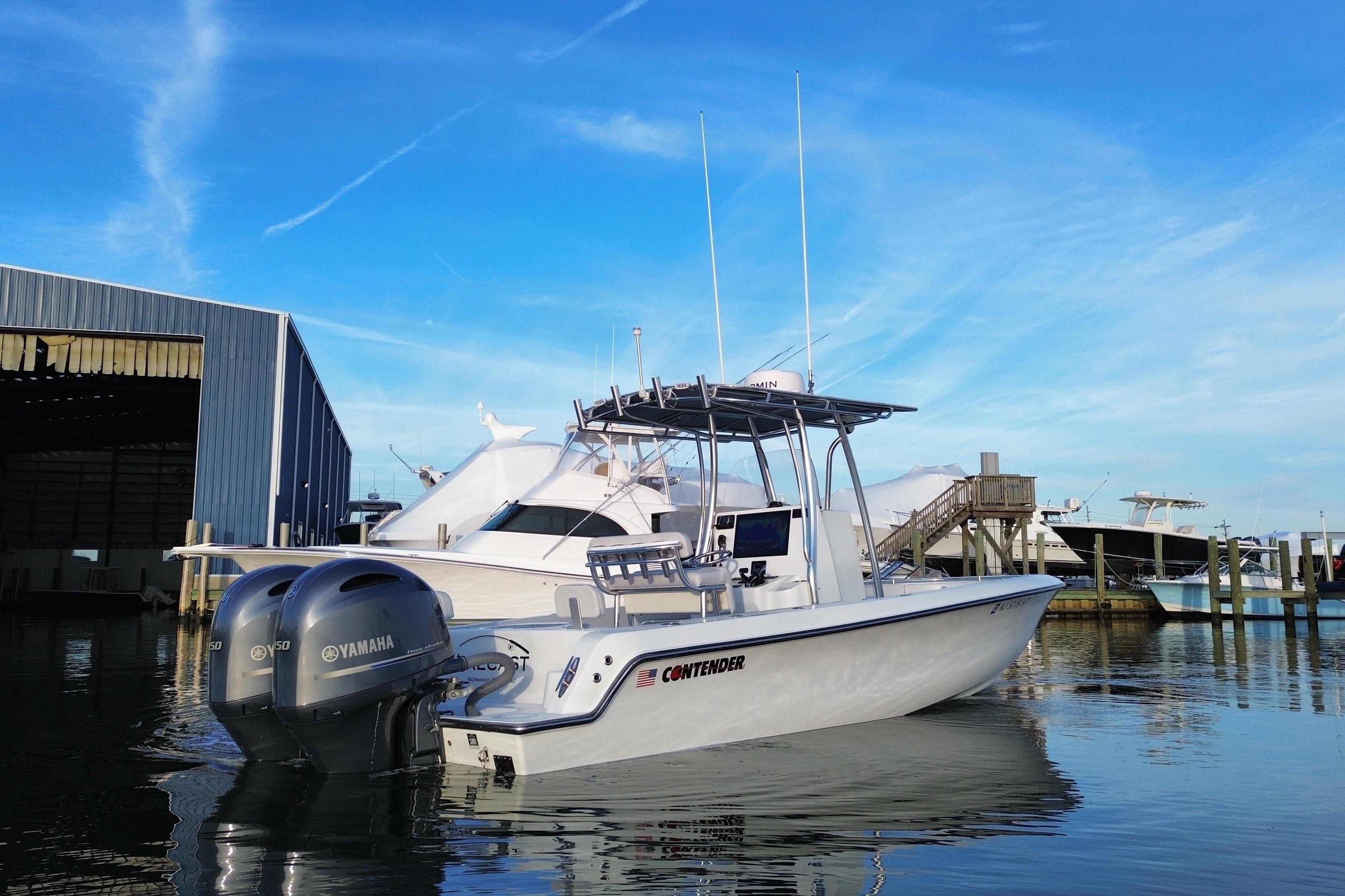 2023 Contender 24 Sport boat docked with Yamaha engines, clear blue sky background.