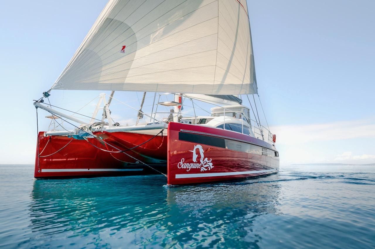 Red Privilege Signature 510 catamaran sailing on calm waters.