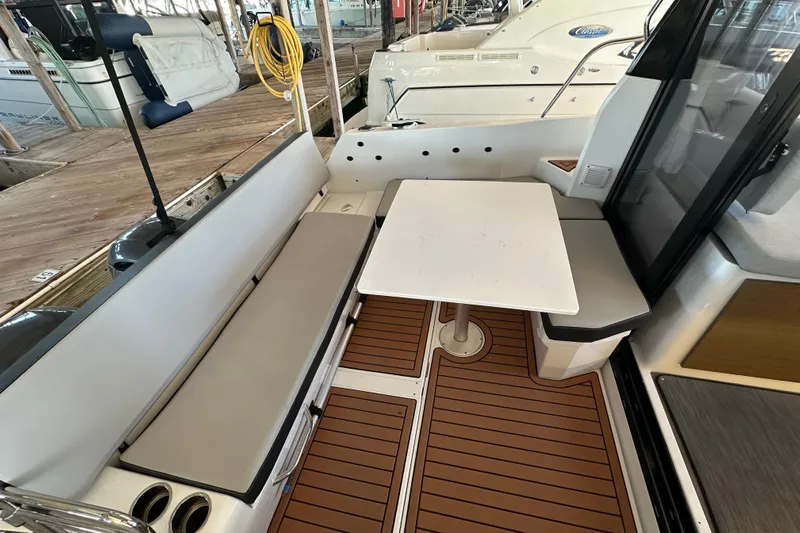 Mauka Makai Yacht Photos Pics 2021 Jeanneau NC 895 boat interior with seating and table on wooden deck.