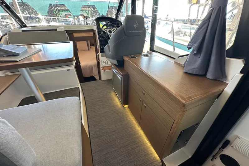 Mauka Makai Yacht Photos Pics Interior of 2021 Jeanneau NC 895 boat, featuring helm, seating, and wooden cabinetry.