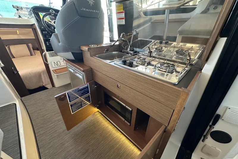 Mauka Makai Yacht Photos Pics 2021 Jeanneau NC 895 interior with kitchenette, featuring stove, sink, and microwave.