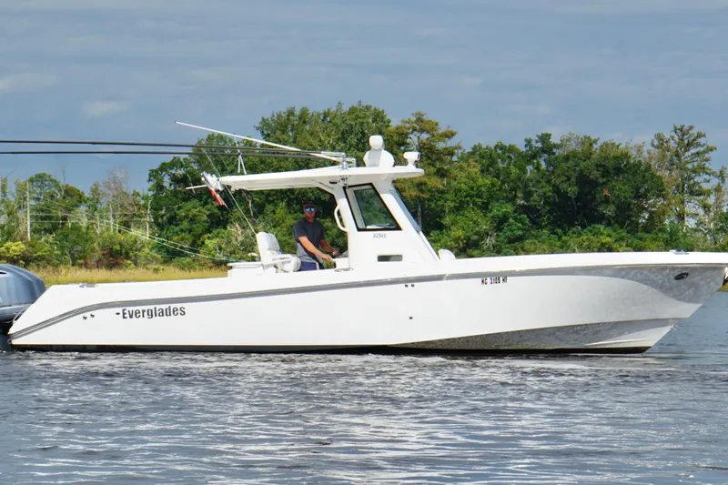  Yacht Photos Pics 2012 Everglades 325 Center Console boat cruising on a calm lake with lush greenery.
