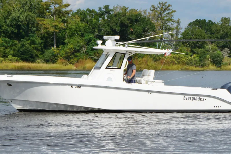  Yacht Photos Pics 2012 Everglades 325 Center Console boat cruising on a calm lake with lush greenery.