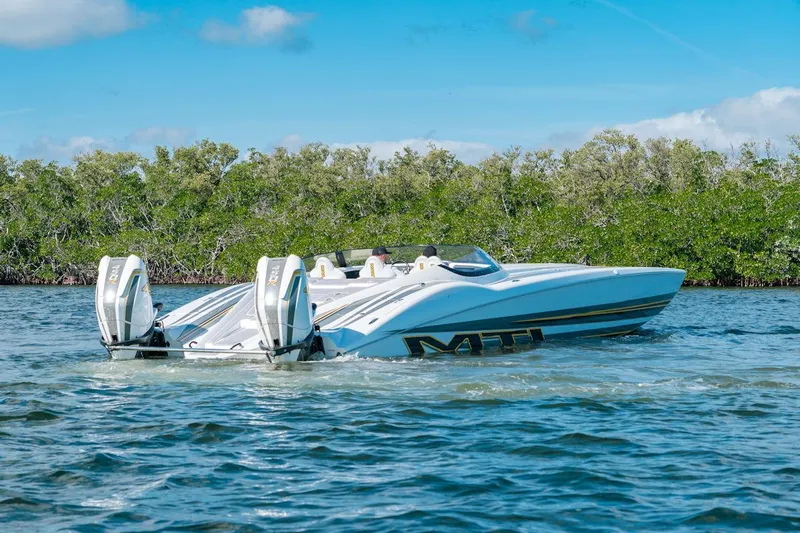  Yacht Photos Pics 2022 MTI 390X speedboat cruising on a sunny day near lush greenery.