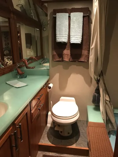  Yacht Photos Pics Bathroom interior of 1977 Monk McQueen 72 CPMY yacht with teal countertop and wooden cabinetry.