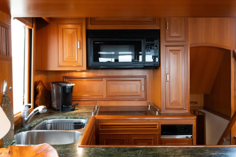 Fiddlesticks Yacht Photos Pics Luxurious wood-finished kitchen in a 2007 Fleming 55 yacht, featuring modern appliances.