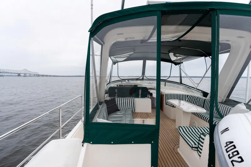 Fiddlesticks Yacht Photos Pics Luxurious 2007 Fleming 55 yacht with striped seating, cruising near a bridge on calm waters.