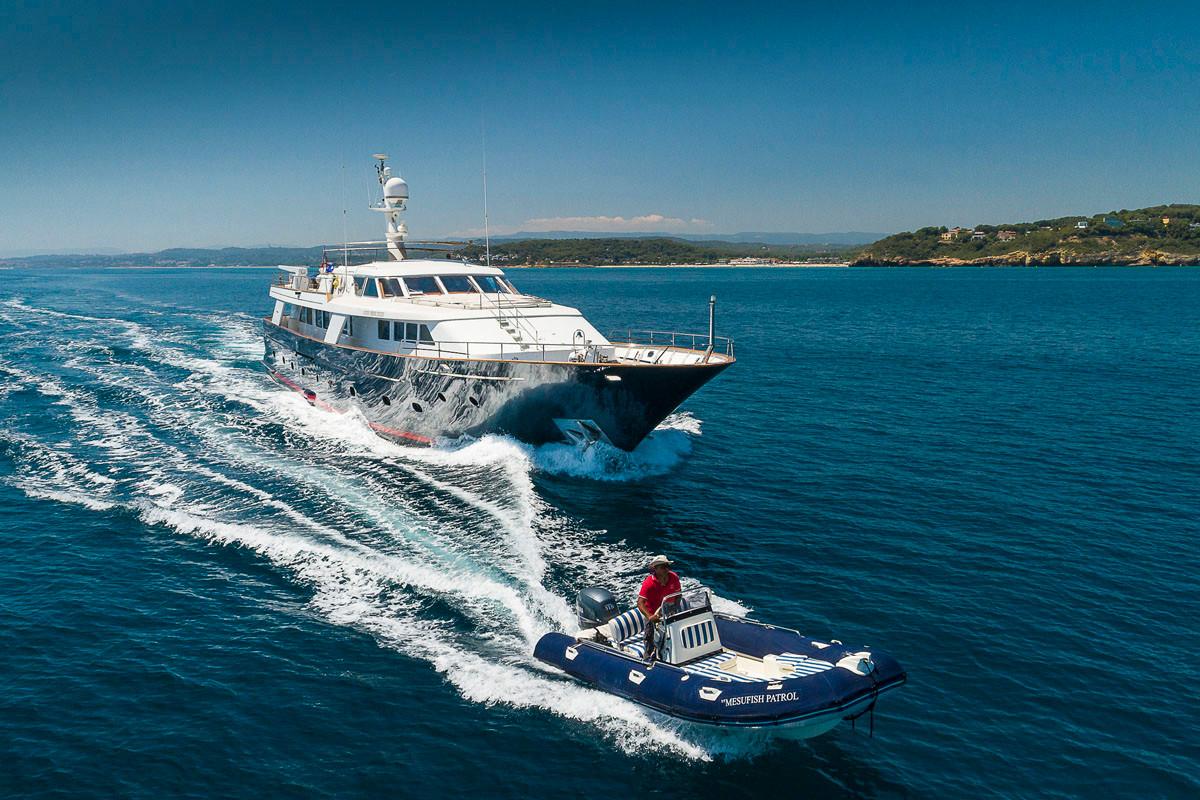 1988 Codecasa Displacement yacht cruising with a small boat in clear blue waters.