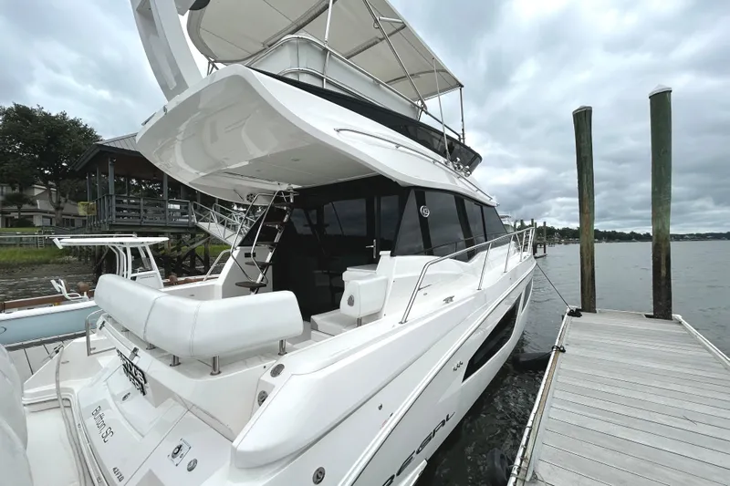 Party's Over Yacht Photos Pics 2024 Regal 42 FXO luxury yacht docked by the water on a cloudy day.