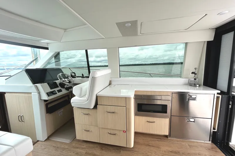 Party's Over Yacht Photos Pics Luxurious interior of 2024 Regal 42 FXO yacht with modern helm and kitchenette.