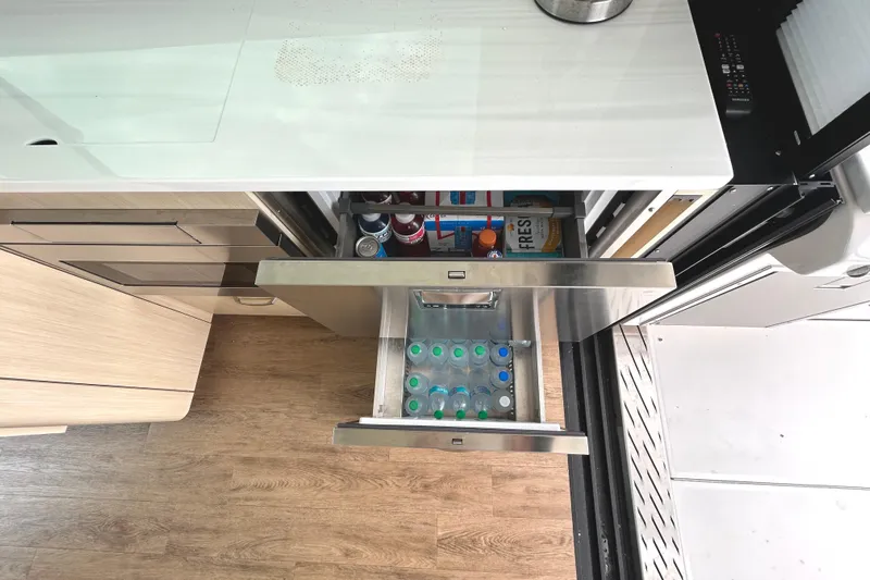 Party's Over Yacht Photos Pics 2024 Regal 42 FXO yacht kitchen with open drawers, showcasing beverages and storage.