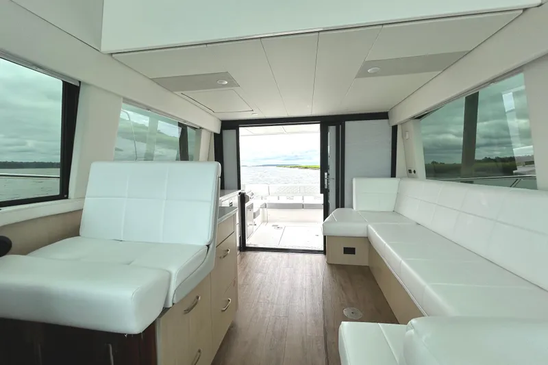 Party's Over Yacht Photos Pics Luxurious interior of 2024 Regal 42 FXO yacht with white seating and panoramic windows.