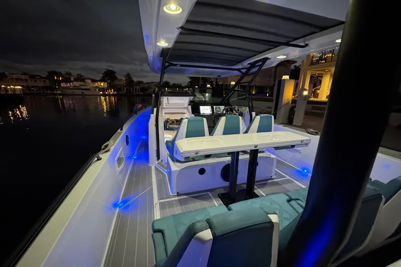  Yacht Photos Pics 2021 Axopar 37 boat interior with blue LED lighting at night, docked by waterfront homes.