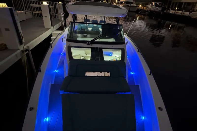  Yacht Photos Pics 2021 Axopar 37 boat with blue LED lights docked at night.
